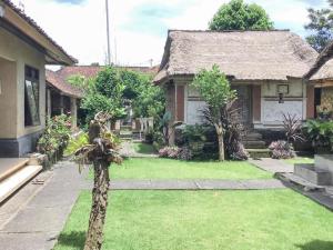 una casa con un jardín con una palmera en el patio en DATON HOUSE near Bali Zoo Ubud Mitra RedDoorz en Darmasaba