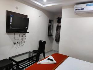 Una habitación con una cama, un televisor y una silla. en Hotel Destiny, en Visakhapatnam 2 fotos más