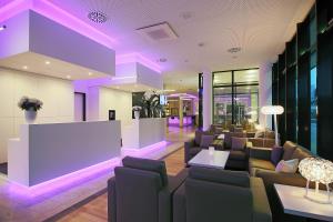 una hall con divani e una sala d'attesa con illuminazione viola di INNSiDE by Meliá Wolfsburg a Wolfsburg