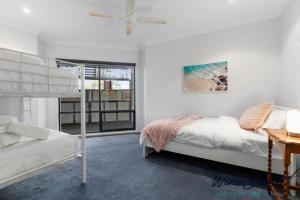 ein weißes Schlafzimmer mit einem Etagenbett und einem Fenster in der Unterkunft Ocean Views and Vineyards by Wine Coast Holiday Rentals in Seaford
