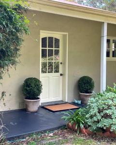 uma porta da frente de uma casa com dois vasos de plantas em Fleetwood Cottage Bed and Breakfast em Mylor