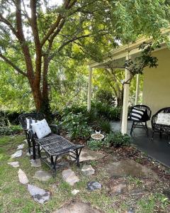 eine Terrasse mit zwei Stühlen und einer Bank im Hof in der Unterkunft Fleetwood Cottage Bed and Breakfast in Mylor