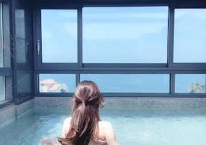 une femme assise à l'eau dans une piscine dans l'établissement Uni Hotel Jeju, à Jeju