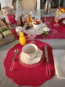 a table with a red table cloth with a plate of food at Au chant des oiseaux in Le Torquesne