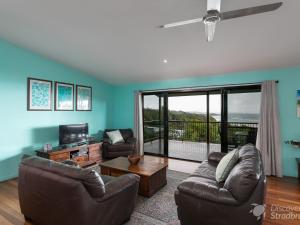 a living room with couches and a television and a balcony at Colours of Cylinder in Point Lookout