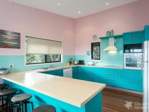 a kitchen with blue cabinets and a counter with stools at Colours of Cylinder in Point Lookout