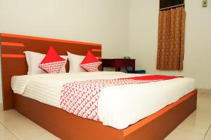 um quarto com uma cama grande e almofadas vermelhas e brancas em OYO Life 189 AA Residence Syariah em Sukarami