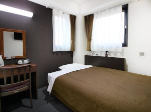 a bedroom with a bed and a desk and windows at Hotel Trend Asakusa Tawaramachi in Tokyo