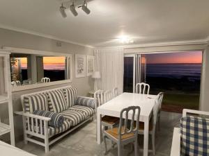 a living room with a table and a couch and a table and chairs at Huis by die See in Hermanus