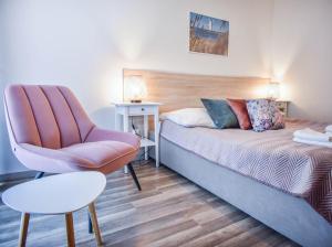 a bedroom with a bed and a chair at Apartamenty na Wyspie - Villa Pegaz - Parking in Świnoujście