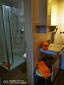 La salle de bains est pourvue d'une douche et d'un lavabo avec des serviettes orange. dans l'établissement Allgäuer Landhaus, à Fischen im Allgäu