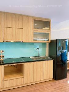 cocina con armarios de madera y nevera negra en Glese Balcony Seaview Apartment - FLC Sea Tower Quy Nhon, en Quy Nhon