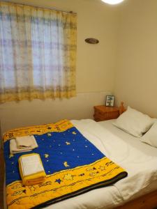 a bed with a blue and yellow blanket on it at Guest House Bovada / Къща за гости Бовада 