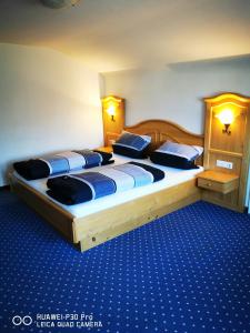two beds in a hotel room with blue carpet at Allgäuer Landhaus in Fischen