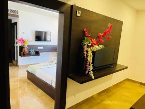 a bedroom with a bed with a tv and flowers at Hotel Elite By Signature Group in Hyderabad