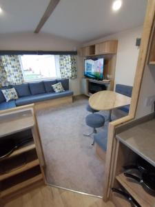 a living room with a blue couch and a table at 69R Seawick 2 Bedroom Caravan . New for 2022 in Saint Osyth