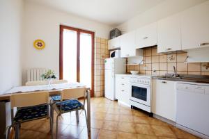cocina con armarios blancos, mesa y sillas en Casa Orchidea - Vista Mare meravigliosa, en Bonassola
