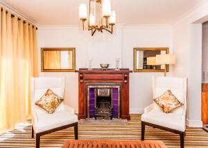 a living room with two chairs and a fireplace at Tudor Barn - Little England Cottages in Nuwara Eliya