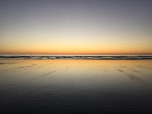 a beach with the sun setting over the ocean at The Ghost Lodge in Granity +88 photos