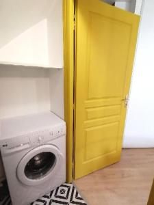- un lave-linge dans une pièce dotée d'une porte jaune dans l'établissement Vannes: charmant studio sur le port, à Vannes