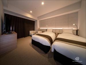 a hotel room with two beds and a television at Daiwa Roynet Hotel Okinawa-Kenchomae in Naha