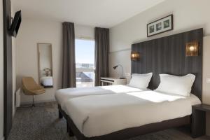 a hotel room with a large bed and a large window at The Originals Boutique, Hôtel d'Alsace, Strasbourg Sud (Qualys-Hotel) in Illkirch-Graffenstaden