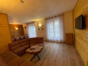 een woonkamer met een bank en een tv bij Appartements avec draps inclus dans le tarif in Lanslebourg-Mont-Cenis