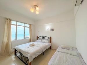 a bedroom with two beds and a window at Maison Seaview Suites Port Dickson in Port Dickson