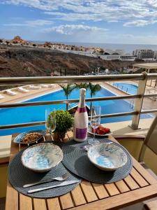 uma mesa com uma garrafa de vinho e pratos de comida em Residencias Sol Paraiso em Adeje