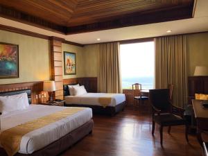 a hotel room with two beds and a desk and a table at Alta D' Tagaytay Hotel in Tagaytay