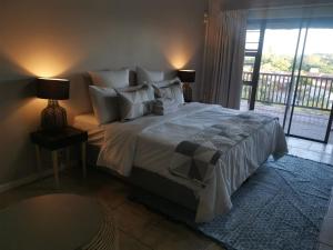 a bedroom with a large bed and a balcony at THE THATCH HIDE in East London