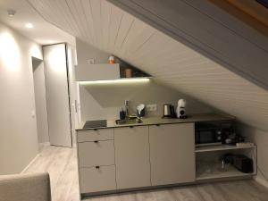 a kitchen with white cabinets and a ceiling at VO apartments in Juodkrantė