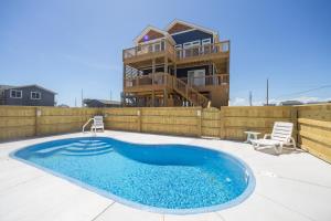 a swimming pool on a patio with a house at The Knotty Whale 120 in Rodanthe