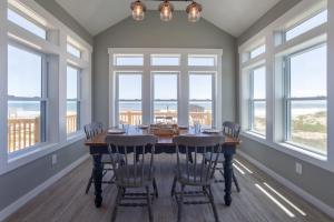 a dining room with a table and chairs and windows at The Knotty Whale 120 in Rodanthe