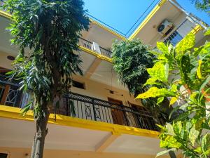 a yellow building with a balcony and palm trees at Lumbini Garden Lodge in Rummindei