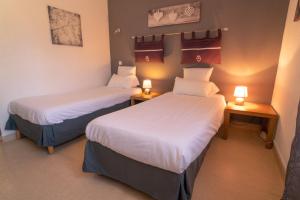 two beds in a room with two lamps on tables at Le President-Gare Nimes Pont Du Gard in Bellegarde
