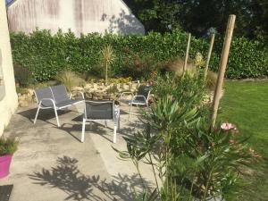 una mesa y sillas en un jardín con flores en Gîte à la campagne, en Pontchâteau