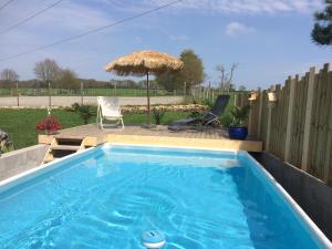 - Piscina con silla y sombrilla en Gîte à la campagne, en Pontchâteau