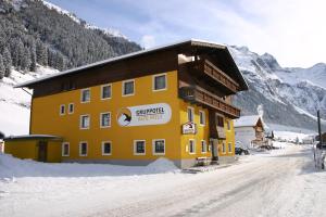 ein großes gelbes Gebäude auf einer schneebedeckten Straße in der Unterkunft Ferienwohnung Alte Post in Sankt Leonhard im Pitztal