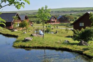 a person sitting on the grass next to a river at Skylark sleeps 8 private Hot Tub & Dogs welcome Nr Padstow, Resort Pool Bar & Watersports in Saint Columb Major
