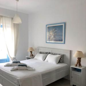 a white bedroom with a bed and two lamps at Villa Molos in Molos Parou