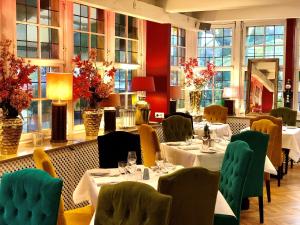 a restaurant with white tables and chairs and windows at Hotel Ashley's Garden in Düsseldorf