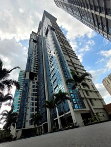 een hoog gebouw met palmbomen ervoor bij Andy's Place One Eastwood Tower 1 in Manilla
