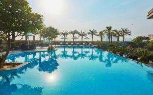 a large blue swimming pool with palm trees and umbrellas at Crowne Plaza New Delhi Rohini, an IHG Hotel in New Delhi