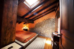 a bedroom with a bed and a stone wall at Posada El Pozu La Tejera in Pontejos