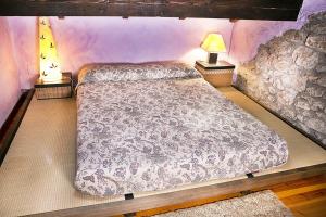 a bed in a bedroom with two lamps on tables at Posada El Pozu La Tejera in Pontejos