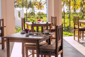 - une table et des chaises en bois dans une chambre avec des palmiers dans l'établissement SBH Kilindini Resort, à Pwani Mchangani