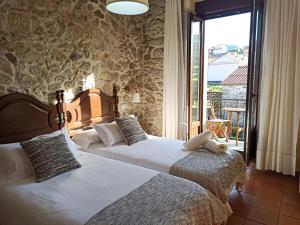 two beds in a hotel room with a balcony at Casa Raúl Lires in Lires