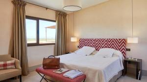 a hotel room with a bed and a chair and a window at Trafalgar Polo Club in El Palmar