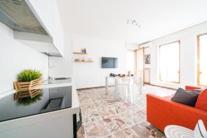 a living room with a red couch and a kitchen at Gardappartamenti Cavour Lake View in Desenzano del Garda